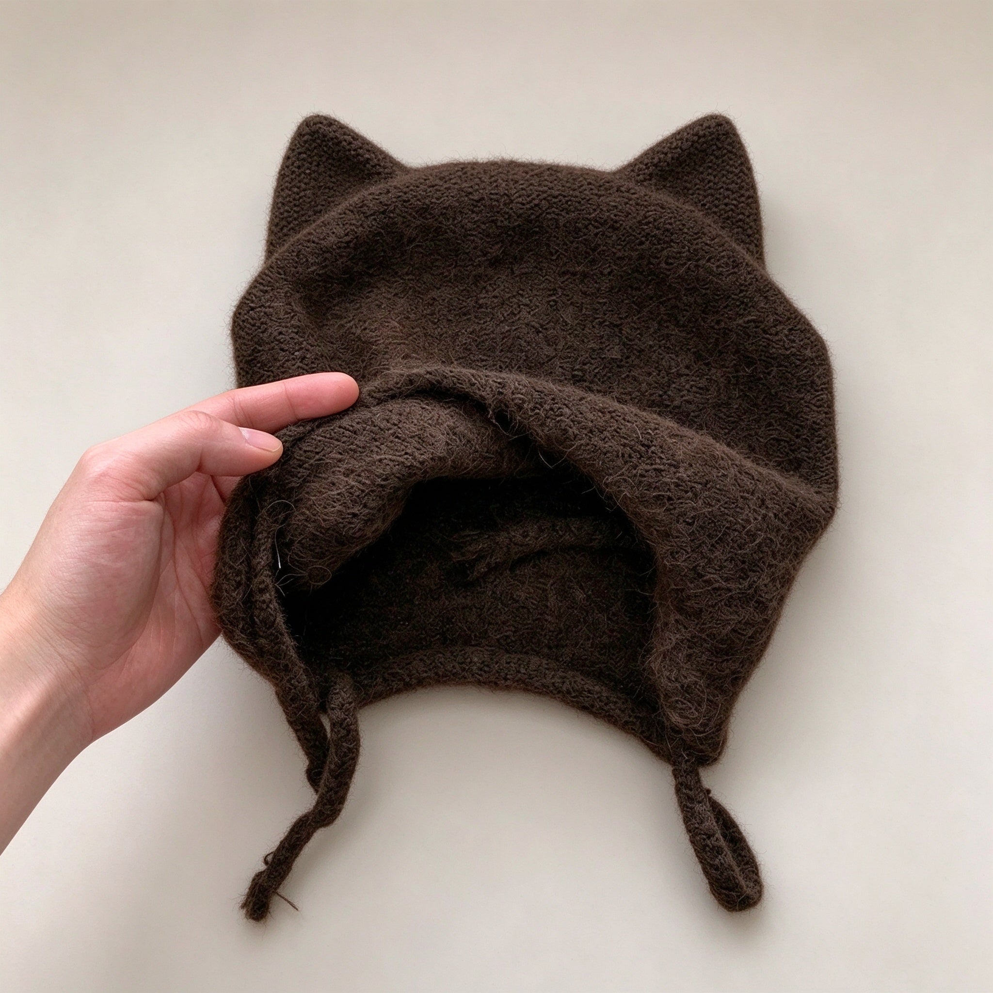Coffee cat ear beanie laid flat, showing the cat ear corners, fuzzy knit and ties