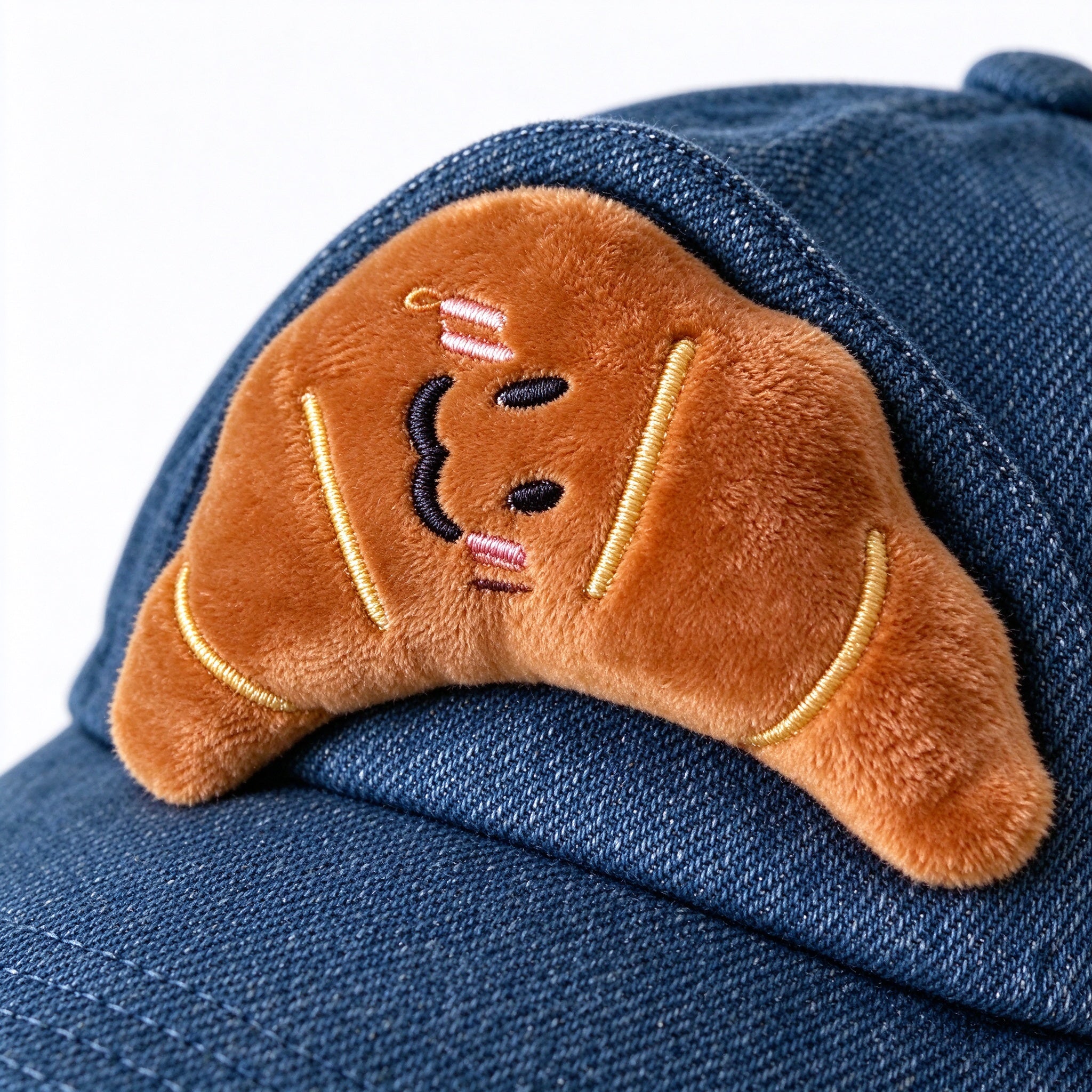 Close-up of the plush croissant ear on dark blue denim