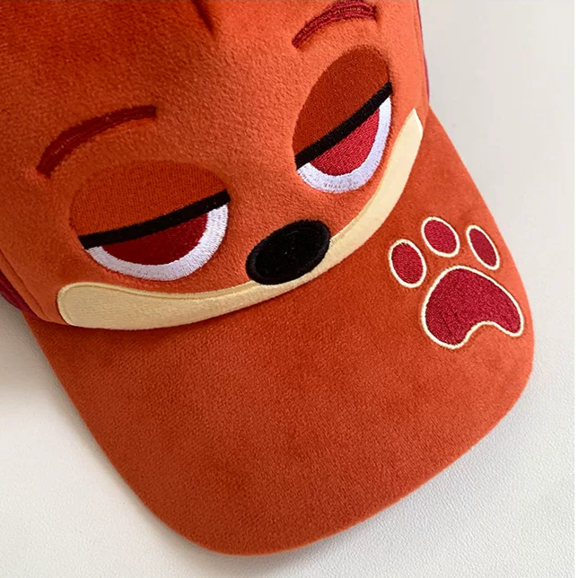 Plush fox baseball cap with embroidered eyes, nose, paw print, and 3D fox ears in soft velvety fabric.